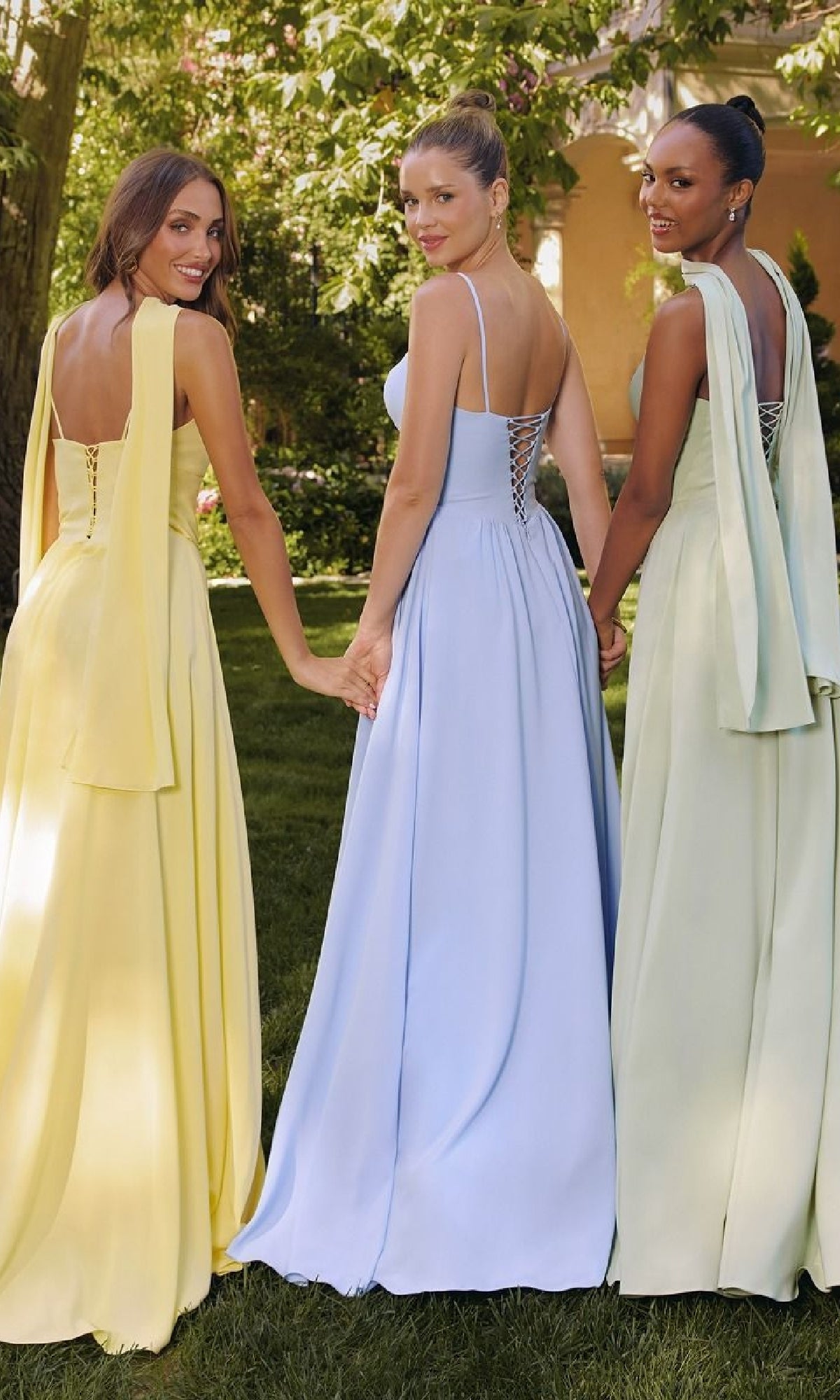Three women in elegant dresses standing outdoors with a blurred background